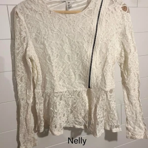 Vit spetsblus med dragkedja från NLY Trend - Säljer en vit blus i spets från NLY Trend. Blusen har lång ärm, blommigt spetsmönster och en cool sned dragkedja framtill. Den har en lätt utsvängd nederdel och rund halsringning. Perfekt för dig som gillar romantiska detaljer med en twist.