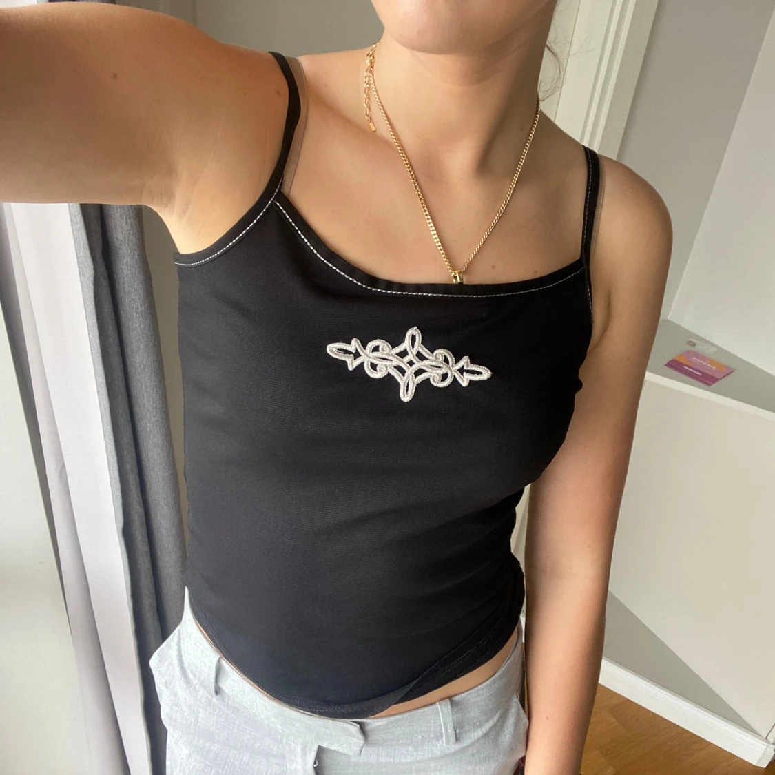 Svart linnetopp med vit broderad detalj