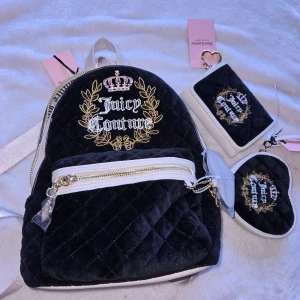 Juicy Couture svart sammet ryggsäck & plånbok - Juicy Couture set med svart quiltad sammet-ryggsäck, matchande plånbok och hjärtformat myntfodral. Alla delar har broderad logga med gulddetaljer och krona, samt vita detaljer och dragkedjor. Perfekt för dig som vill sticka ut med en lyxig och trendig look.