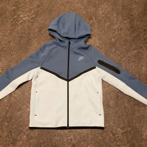 Nike tech fleece blå/vit - Blå/vit Nike tech fleece hoodie med huva,den är i nyskick helt oanvänd och storlek 158-170 säljes vid fast pris men säljes billigare vid snabbare affär 