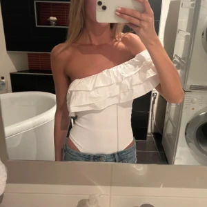 Vit one shoulder body med volang - Jättefin Zara body i storlek S, helt nyskick! Lånade bilder men kan såklart skicka egna! Diskuterbart pris vid snabb affär❤️