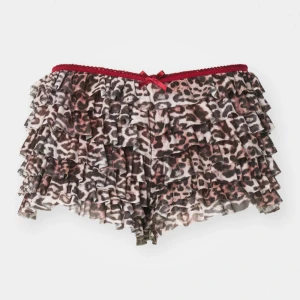 Leopardmönstrade volangshorts ifrån jaded london - Supersöta shorts med leopardmönster och flera lager volanger. Midjan har en röd spetskant och en liten rosett framtill som extra detalj. Perfekta för dig som vill sticka ut och älskar djurmönster.