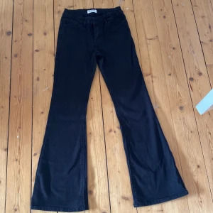 Svarta bootcut byxor från Lindex - Svarta byxor från Lindex i modellen Freja, storlek 146. Byxorna har klassisk femficksdesign, bälteshällor och bootcut-ben som ger en snygg siluett. Materialet är mjukt och stretchigt, perfekt för en trendig och bekväm look. Med frakt 40kr
