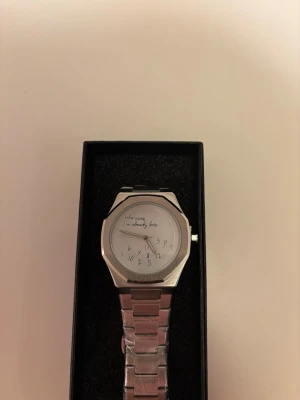 Rolex liknande klocka -  Silvrig Rolex liknande klocka med texten 'Who cares, I'm already late' på urtavlan och ett metallarmband.