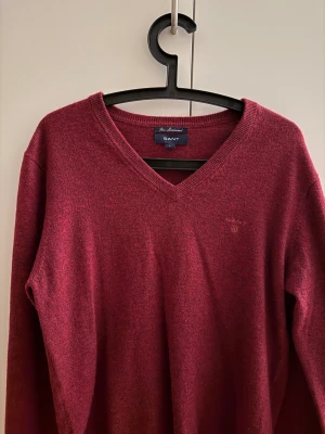 Vinröd ulltröja GANT - Vinröd stickad tröja från GANT i 100% lammull. V-ringad hals och diskret broderad logga på bröstet. Klassisk modell med lång ärm och ribbade muddar. Perfekt för dig som gillar stilrena och bekväma plagg med premiumkänsla. I mycket bra skick. Knappt använd av mig. Hör av er vid frågor/funderingar. 
