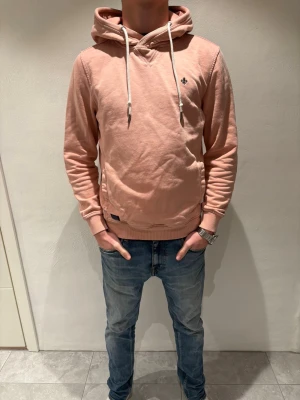 Morris hoodie - Snygg ljusrosa hoodie från Morris med en broderad logga på bröstet. Mjuk bomullskänsla och avslappnad passform, perfekt för chill dagar. Storleken är i S.