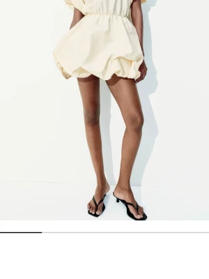 Ljus kortklänning med puffärmar - Superfin ljus kortklänning med puffiga ärmar och ballongformad kjol. Klänningen har en markerad midja med resår och är tillverkad i ett lätt material som ger en luftig känsla. Perfekt för varma dagar och ger en trendig vibe. Aldrig använd och har lappen kvar