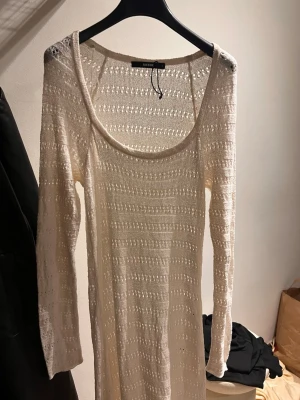 Vit lång stickad klänning Bikbok - Säljer en vit lång stickad klänning från Bikbok i storlek L. Klänningen har ett snyggt hålmönster, rundad urringning och långa ärmar. Perfekt för dig som gillar en chill och bohemisk stil. Materialet är stickat och känns mjukt mot huden.
