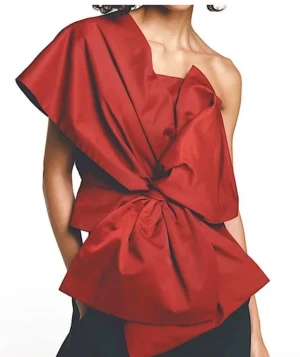 Röd oneshoulder topp med stor rosett - Säljer en unik röd topp med oneshoulder-design och en stor, iögonfallande rosett framtill. Toppen har en asymmetrisk form och är tillverkad i ett slätt tyg som ger en cool och modern look. Perfekt för dig som vill sticka ut och gillar statement-plagg. Använd 1 gång förra julen.