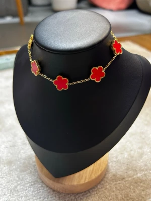 Elegant klöverarmband med röda detaljer  - Vackert klöverarmband i guldfärgad ton med djup röda klöverdetaljer som ger ett lyxigt och tidlöst intryck. Ett stilrent smycke som passar lika bra till vardag som till fest.  Armbandet är elegant, feminint och lätt att matcha – en perfekt present eller ett fint tillskott till din smyckessamling ❤️