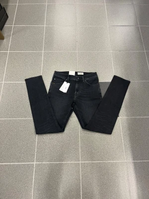 Svarta slim  jeans från Tiger of sweden W28 L32 - Säljer ett par svarta jeans från T/J med slim fit. Klassisk femficksdesign och snyggt diskret läderpatch bak i midjan. Materialet är mjukt jeans-tyg som sitter riktigt bra och ger en clean look.