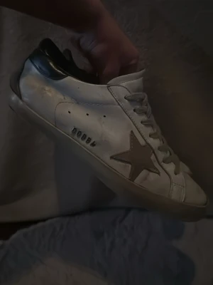Golden Goose  - Säljer ett par vita Golden Goose.  Skorna har svart häl och platt brun sula. Skick okej. Har haft dom ett bra tag nu, och därför är dom inte i det bästa skicket. Tyvär ingen box eller dustbeg. Skriv gärna om du har några funderingar😊
