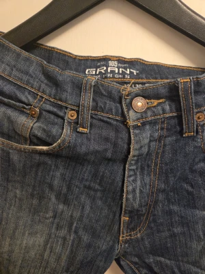 Grant 305 jeans blå W32 L30 - Säljer ett par klassiska blå jeans från Grant, modell 305. Jeansen har fem fickor, snygga kontrastsömmar och rak passform. Materialet är slitstarkt denim i bomull och färgen är mörkblå med lätt tvättad look. Perfekt för dig som gillar enkel och tidlös stil.