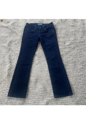 Mörkblå bootcut jeans från Lee - Snygga mörkblå jeans från Lee med klassisk femficksdesign och bootcut-ben lågmidjade. Midjemått ca 39 cm innerbenslängd ca 80 cm. Enda defekten är lite slitna långst ner men syns knappt när man har dem på sig. Köpta för ca 1900 kr. Långa på mig som är 1.57