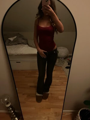 Vinröd body - Säljer en vinröd vinröd med smala axelband och figurnära passform. Toppen har en enkel och stilren design. Materialet känns mjukt och följsamt mot kroppen. Färgen är djup vinröd och toppen är ärmlös.