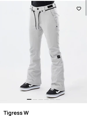 Vita täckbyxor Tigress W med snörning - Snygga vita snowboard byxor från dope med svart snörning i midjan och bälteshällor. Byxorna har en bootcut-passform och resor band i midjan så man kan göra midjan mindre och större. Perfekta för vintern till både skid och snowboard åkning, nypris 1799 de är använda en gång