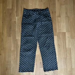 Svarta jeans med grått mönster från Jaded London - Unika svarta jeans från Jaded London med grått prickigt mönster och råa kanter vid benslut. Modellen har fem fickor, knapp och dragkedja framtill samt bälteshällor. Materialet är jeans med en cool textur och mönster som sticker ut. Klippta längst ner för bättre passform. Passar mig bra och är 1.78. Pris kan diskuteras