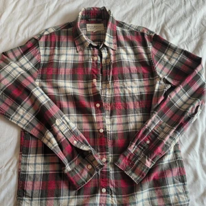 Rutig skjorta från Ralph Lauren S - Säljer en klassisk rutig skjorta från Denim & Supply Ralph Lauren i storlek S. Skjortan har röda, gröna, vita och blå toner, lång ärm, bröstficka och knappar framtill. Tillverkad i mjuk bomull, perfekt för en avslappnad och cool look.