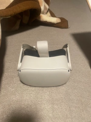 Meta Quest 2 VR-headset - Meta Quest 2 VR-headset med två handkontroller och originalkartong. Enheten ser ut att vara i gott skick utan synligt slitage. Perfekt för uppslukande VR-upplevelser och spel. Allt som behövs för att komma igång med virtuell verklighet ingår.