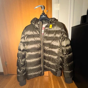 Parajumpers Sheen pufferjacka XL - Säljer en sprillans ny Parajumper Sheen. Jackan är inköpt för ca 1.5 månad sedan från Johnells (KVITTO OCH TAGS FINNS!) och använts maximalt 5x. Inga defekter eller konstigheter, utan den är i absolut nyskick. Inköpspris: 7 200kr. Färgen är grön/brun, den finaste enligt mig.                    https://www.careofcarl.se/sv/parajumpers-pharrell-sheen-high-gloss-jacket-toubre-green
