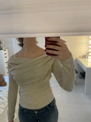 Beige omlott topp - Säljer en beige omlott topp från SHEIN i storlek S. Toppen har lång ärm och en snygg offshoulder-design med omlott-detalj över bröstet. Materialet är mjukt och stretchigt.