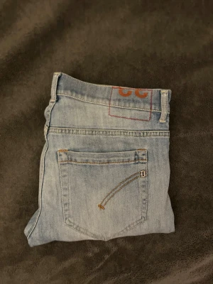 Dondup jeans - Säljer ett par ljusblå jeans från Dondup. Har en lite slitning på framsidan som man ser. Jeansen har klassisk femficksdesign, raka ben och normal passform.