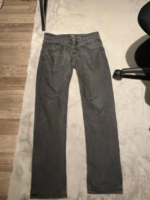 Replay Grover svarta jeans straight fit - Säljer ett par Replay Grover jeans i svart tvättad färg med straight fit. Klassisk femficksmodell med Replay-logga på fickan och bak på linningen. Jeansen är tillverkade i jeansmaterial och har normal passform. Perfekt för dig som gillar stilrena och tidlösa jeans. Storlek 
