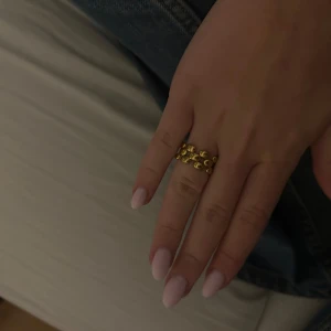 Chunky guldpläterad ring med bubblor - Säljer en chunky ring i guldpläterad metall med coolt bubbligt mönster. Ringen har en bred design med två rader av upphöjda, runda detaljer som ger en unik och trendig look. Perfekt statement-piece för dig som gillar att sticka ut.