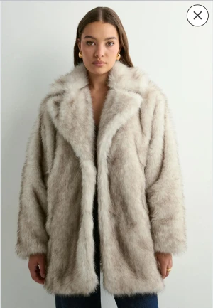 Beige pälsjacka med oversized passform - Säljer en fluffig och oversized beige pälsjacka med bred krage och långa ärmar. Jackan har en lyxig känsla och är perfekt för att hålla värmen under kyliga dagar. Den har en rak siluett och är enkel att styla till olika outfits.