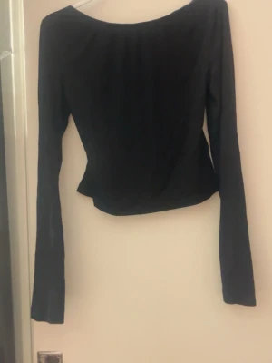 Svart långärmad topp från SHEIN - Svart långärmad topp från SHEIN i storlek S. Toppen har en snygg öppen rygg och är figurnära med en enkel, stilren design. Materialet är mjukt och stretchigt, perfekt för att skapa en cool look. Passar dig som gillar minimalistiska plagg med en twist.