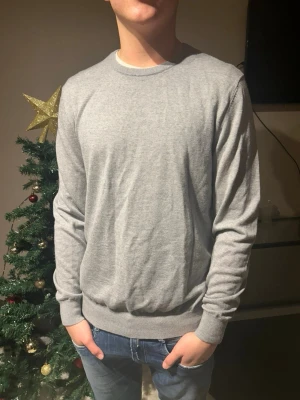Grå stickad tröja Tiger of Sweden - Snygg grå stickad tröja från Tiger of Sweden i storlek M. Tillverkad av fin italiensk garn, med rund hals och ribbade muddar vid ärmslut och nederkant. Perfekt för dig som gillar stilrena och klassiska plagg. Skriv om du har frågor eller funderingar‼️