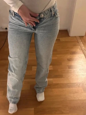  ljusblå raka jeans - Ljusblå jeans med klassisk rak passform och hög midja. Jeansen har fem fickor, knappgylf och är tillverkade i robust denim. Perfekta för en avslappnad och tidlös look.