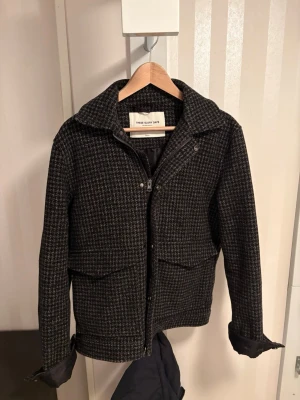 Rutig overshirt från These Glory Days - Snygg rutig overshirt i mörkgrå och svart från These Glory Days. Jackan har klassisk krage, två stora fickor framtill och stängs med både dragkedja och knappar. Materialet är ullblandning som ger en skön och varm känsla. Perfekt för höst och vinter.