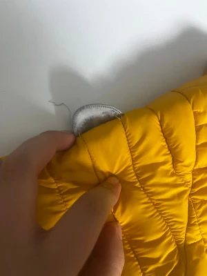 Gul pufferjacka Polarn O. Pyret 86 - Snygg gul pufferjacka från Polarn O. Pyret i storlek 86. Jackan har quiltad design, dragkedja framtill och reflexdetalj på ryggen. Perfekt för kyliga dagar och enkel att matcha med andra plagg.