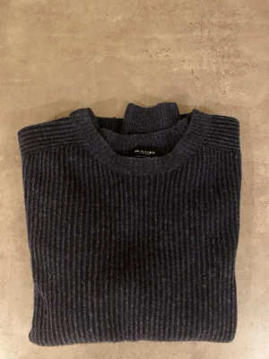 Mörkblå stickad tröja från Sand - Snygg mörkblå stickad tröja från Sand Copenhagen med ribbad struktur och rund hals. Endast använd fåtal gånger, köpt på NK i Göteborg, nypris ca 2000