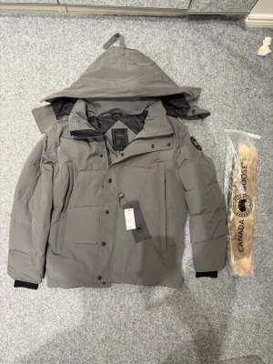 Canada Goose wyndham gray parka -Black badge - Its a bit damaged on the last image. Other than that its just as new. Size fusion M, bought on Vinted with item verification so it was verificated to be 100% real. Please feel free to ask any questions, receipt available via DM.