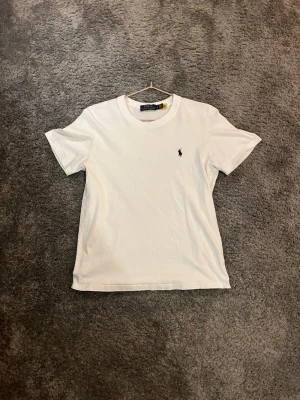 Vit t-shirt från Polo Ralph Lauren - Klassisk vit t-shirt från Polo Ralph Lauren med liten broderad logga på bröstet. Storlek S och passar dig som är ca 165-180. Jättefint skick. MVH 