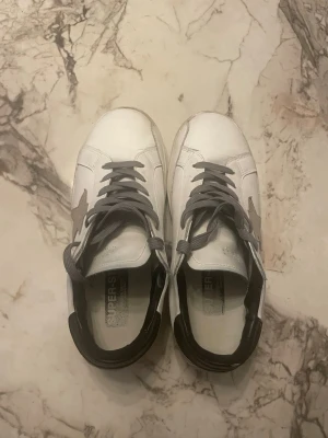Golden Goose vita sneakers med stjärna - Hej nu är det dags att sälja min gdg skor. Jag har haft de nu ett dag men har tyvärr växt ut ur de. De är väl använda skicket är 7/10 därav priset. De har fortfarande mycket att ge och är stilrena och uppmärksamma. De är 41 men passar även 40
