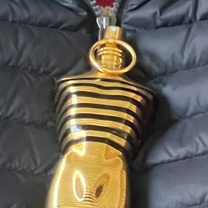 Le Male Le Parfum Eau de Parfum - Säljer en ikonisk herrparfym från Jean Paul Gaultier, Le Male Le Parfum. Flaskan är formad som en manlig torso i glänsande guld med svarta ränder och detaljer. Perfekt för dig som gillar lyxiga och unika dofter.