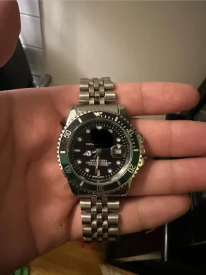 Klocka - Hej säljer bort en stil ren klocka med grön och svart krans. Klockan kommer med boxen som är på bilderna  den är helt ny aldrig använd. Den är 40mm ni kan hämta den om ni vill eller så kan jag skicka den 😁om ni har andra frågor de ba ställa. står inte för strul/problem med posten 