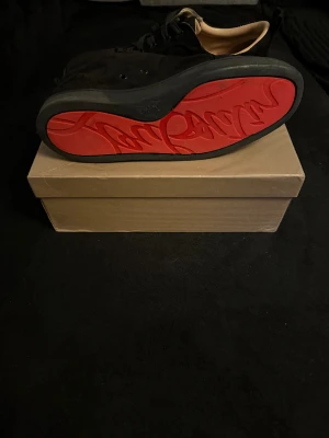 Christian Louboutin svarta mockasneakers - Skick 8/10 priset går att diskutera vid snabb affär.Svarta sneakers från Christian Louboutin i mjuk mocka med klassisk röd sula och diskret logga. Skorna har rund tå, platt sula och svarta snören. Insidan är beige och har lyxig känsla. Säljes med originalkartong och dustbag med Louboutin-tryck.