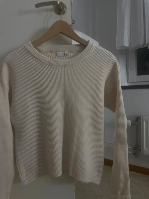 Beige ribbad stickad tröja Basic Needs - Säljer en beige stickad tröja från Basic Needs i storlek S. Tröjan har ett ribbat mönster, rund halsringning och långa ärmar. 