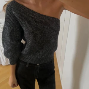 Glittrig svart oneshoulder stickad topp - Säljer en snygg svart stickad topp med glittriga inslag. Modellen är oneshoulder med en ärm och croppad passform. Perfekt till fest och nyår!