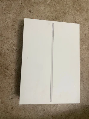 iPad Air 2 Wi-Fi + Cellular 64GB Silver - Apple iPad Air 2 med 64GB lagring, Wi-Fi + Cellular, i silver. Levereras i originalkartong. Några synliga repor och märken på baksidan, skärmen har fingeravtryck men inga tydliga sprickor. Perfekt för surf, appar och underhållning.