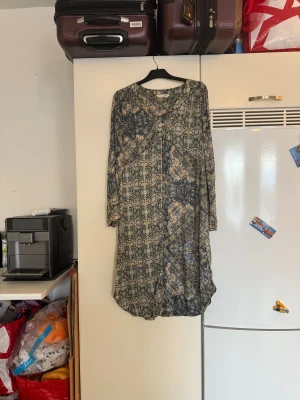 Mönstrad långklänning Odd Molly - Säljer en superfin klänning med v-ringning och långärmade ärmar. Klänningen har ett detaljerat blommigt mönster i blått, beige och grönt. Materialet är mjukt och följsamt, perfekt för dig som gillar boho-vibe och snygga prints. Från märket Odd Molly. Storlek 2 som enligt deras storleksguide motsvarar en M. Mycket fint skick, jag hittar inga synliga anmärkningar eller defekter. 