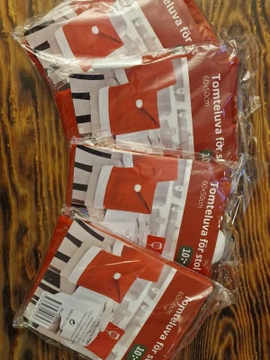 4 stycken röda tomteluvor för stol 60x50cm - Tomteluva för stol i klassisk röd färg med vit kant och liten vit boll. Perfekt för att ge din stol en julig vibe. Säljes nytt i förpackning, designad för att passa de flesta stolar.