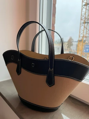 Beige och svart handväska från H&M - Snygg handväska från H&M i beige och svart. Man kan ha den både crossbody eller hålla i handen! Fick den i födelsedagspresent får nån månad sen och har aldrig använt. Med andra ord så är den i nyskick! Nypris är runt 350kr. Tveka inte vid frågor! Pris kan diskuteras men kommer inte acceptera för höga sänkningar!💕💕