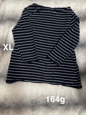 Svartvit randig långärmad topp XL - Säljer en svart långärmad topp med vita horisontella ränder i storlek XL. Toppen har en klassisk rund hals. Perfekt för en chill och stilren look.🌸 Sparsamt använd. Storlek XL