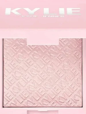Kylie Jenner highlighter i ljusrosa - Highlighter från Kylie Jenner i en snygg ljusrosa förpackning med spegel. Pudret har en skimrande, kall rosa ton och är pressat med mönster och logga. Perfekt för att ge glow till kindbenen eller andra delar av ansiktet.