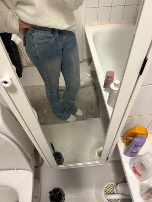 True Religion Becca Bootcut Jeans - Snygga ljusblå jeans från True Religion, modell Becca Mid Rise Bootcut. Klassisk femficksdesign med medelhög midja och bootcut-ben. Jeansen har slitningar och tvättade detaljer som ger en cool vintagekänsla. Perfekt för dig som gillar avslappnad stil.